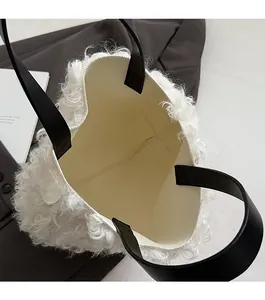 Close-up of white plush bucket bag with black leather handle and spacious open interior