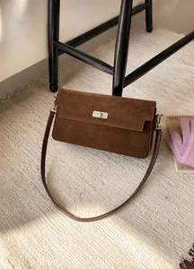 Close-up of dark brown suede shoulder bag featuring a vintage silver metal twist lock