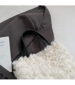 Detail of soft white faux fur handbag with sleek black leather handle and plush texture