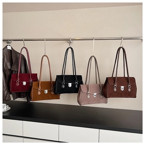Detailed display of five colorful vintage suede tote bags hanging with metal lock closures