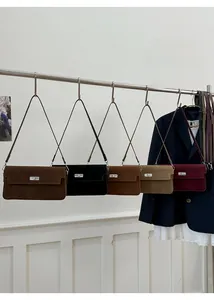 Detail view of five matte suede shoulder bags in autumn colors with silver rotating locks