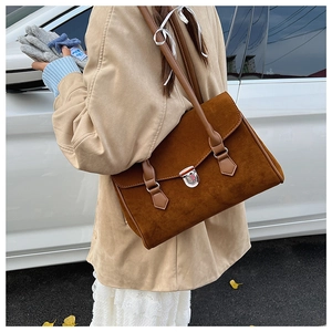 Close-up of brown suede hobo bag with silver buckle worn with a beige trench coat