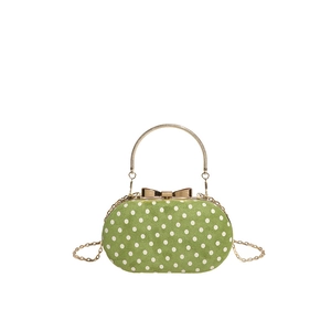Green polka dot suede crossbody bag with gold bow clasp and metallic handle