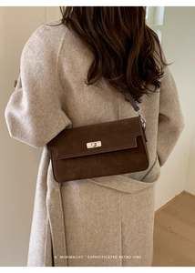Close-up of matte dark brown suede shoulder bag with silver metallic twist lock on a model