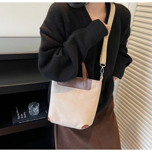 Detail of beige tote bag with brown leather trim and wide fabric shoulder strap