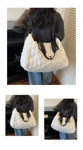 Detail showing white quilted puffer tote bag with black wide straps and silver metal hardware
