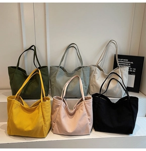 Collection de sacs cabas en velours côtelé coloré présentés sur un support blanc à niveaux