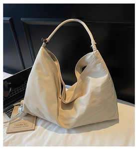 Close-up of beige crescent bag with textured fabric and dark wooden bead details