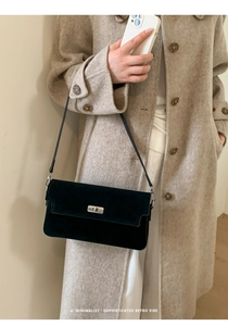 Detail of a black suede retro shoulder bag featuring a silver metal twist lock closure