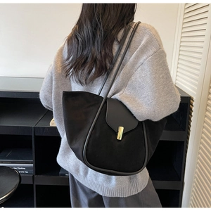 Detail of black suede tote bag featuring a gold rectangular clasp and leather flap closure