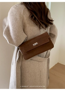 Brown suede crossbody bag detail showing retro minimalist design on a wool coat