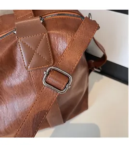 Detailed view of brown leather bag with adjustable strap, silver buckle, and reinforced stitching