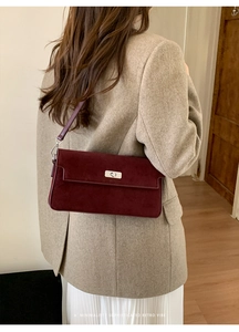 Detail view of burgundy suede handbag with silver metal twist lock and matte finish