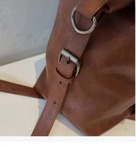 Macro shot of retro brown leather bag showing brushed metal buckle and stitching detail