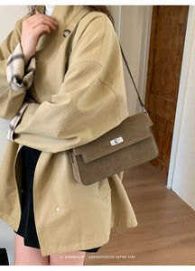 Close-up of brown suede shoulder bag with silver metal buckle on a khaki trench coat