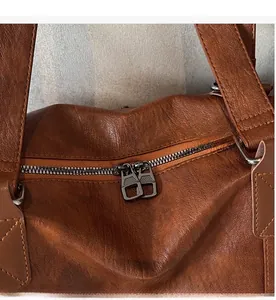 Detail of smooth metal double zippers and leather texture on a vintage brown travel bag