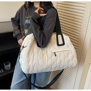 Detailed macro view of white quilted travel tote featuring geometric embroidery and black strap