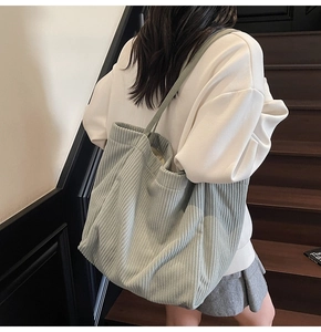 Modèle portant un sac cabas en velours côtelé vert clair avec grande capacité et texture