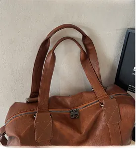 Macro view of caramel brown leather tote handle with reinforced cross stitching and silver zipper