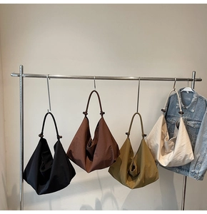 Close-up of pleated tote bags with knot detail in black, brown, yellow and beige