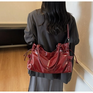 Détail d'un sac cabas bordeaux brillant avec texture plissée à cordon et longues anses