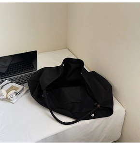 Detail shot of the black tote bag showing magnetic closure and interior pocket compartment