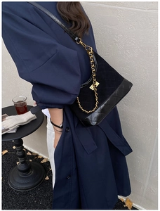 Close-up of black quilted crossbody bag with gold chain strap in a lifestyle outdoor setting