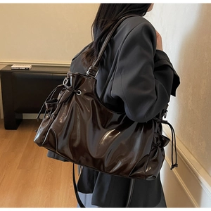 Détail du sac cabas en cuir verni marron foncé avec cordon de serrage et boucles argentées