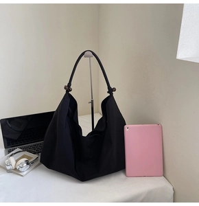 Close-up of black slouchy tote bag featuring elegant wooden bead details on the strap