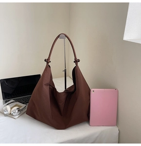Detail of dark brown hobo bag with wooden bead strap detail shown in a home office setting