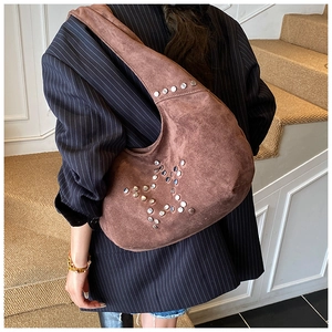 Detail of dark brown suede hobo bag with silver star-shaped rivet studs on shoulder