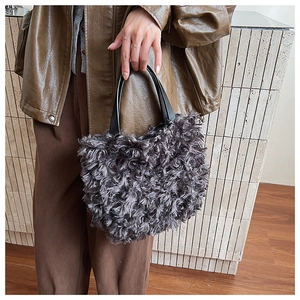 Detail of grey fluffy faux fur bucket bag with black leather handle and rich texture