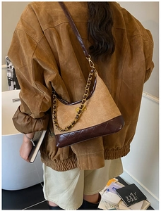 Detail showing the quilted brown leather textures and gold chain strap of the crossbody bag
