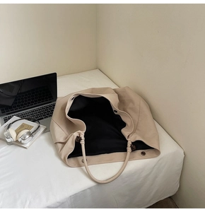 Detail of minimalist beige tote bag with wooden bead strap decor on a soft bed