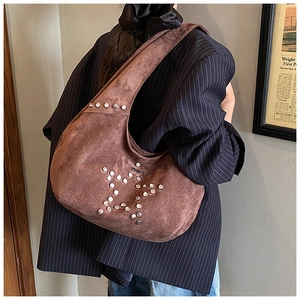 Detail view of suede underarm bag featuring silver rivet star design and zip closure