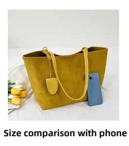 Detailed view of yellow suede tote bag capacity with a phone for size comparison