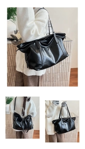 Detail of a large black oil-wax leather tote bag with handles and adjustable shoulder strap