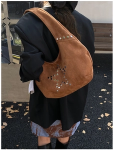 Detail of brown suede hobo bag with silver metallic star studs and wide shoulder strap