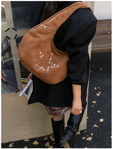 Detail of brown suede crescent bag with silver stud star pattern on a city street