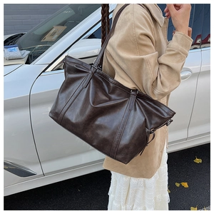 Détail d'un cabas vintage en simili cuir marron foncé avec boucles métalliques de réglage