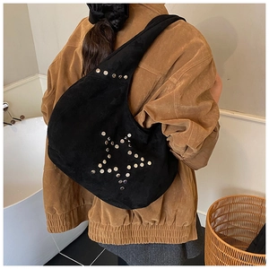 Detail of black suede hobo bag with silver stud star pattern worn with brown jacket