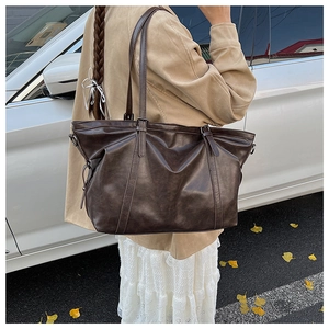 Detail of vintage dark brown faux leather tote bag with adjustable shoulder strap outdoors
