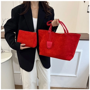 Detail of red suede tote bag set featuring large trapezoid bag and matching zipper clutch