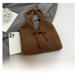 Detail of dark brown knit tote bag with bow knot and thick knit texture close-up
