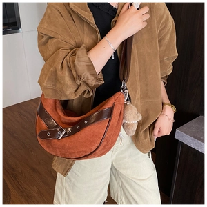 Detail van oranje suède hobo tas met bruine leren riem en schattige pluche beer hanger