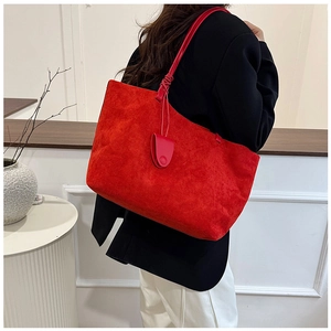 Detailed view of a large red matte suede tote bag worn on shoulder in a modern room