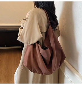 Brown canvas hobo bag with knot detail shown on model in khaki trench coat