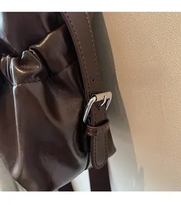 Detail of silver metal buckle and shiny brown oil wax leather on a vintage bag