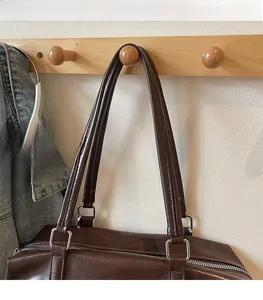 Close-up of brown oiled leather tote bag with silver square metal buckle detail