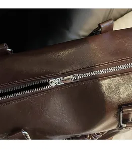 Close-up of durable silver metal zipper and brown litchi grain leather on handbag